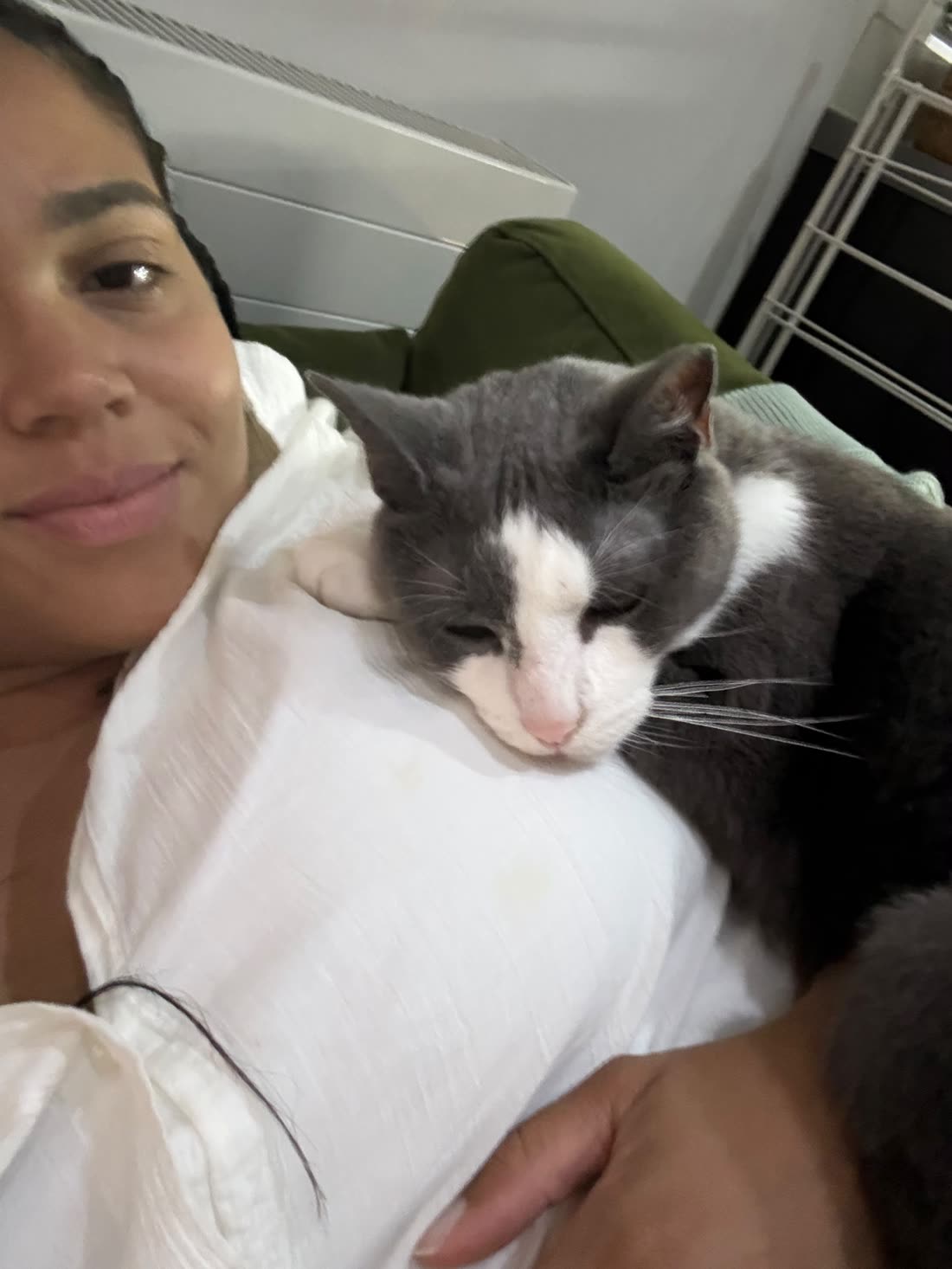 Shareefa on the sofa with a grey and white cat fast asleep on her chest