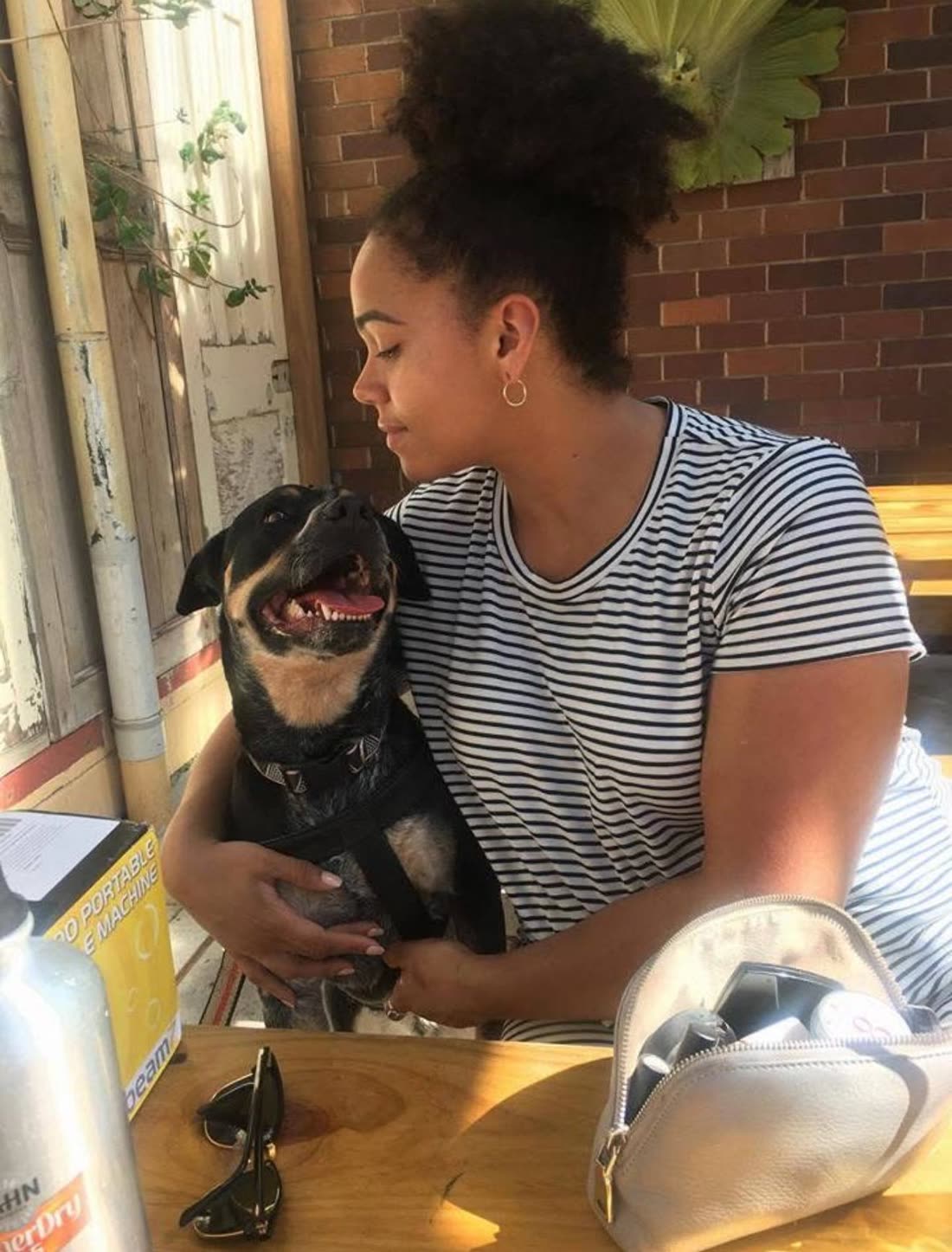 Shareefa smiling at a very happy black-and-tan dog sitting on her lap